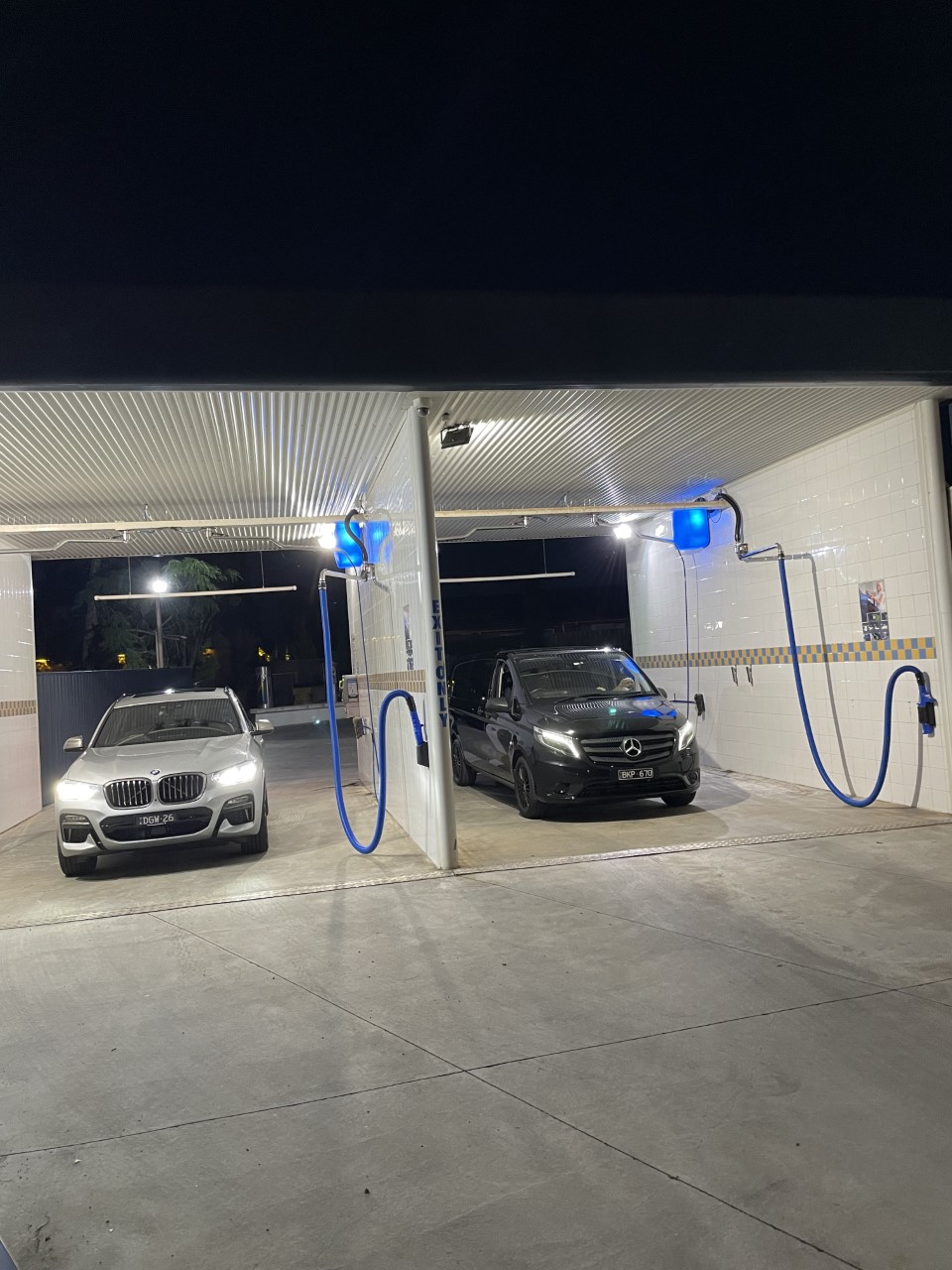The manual wash bays at Swift Car Wash lit up at night with two vehicles inside